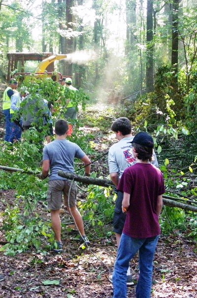 Volunteers from the Boy Scouts of America drag downed brush to a chipper operated by NPS staff.