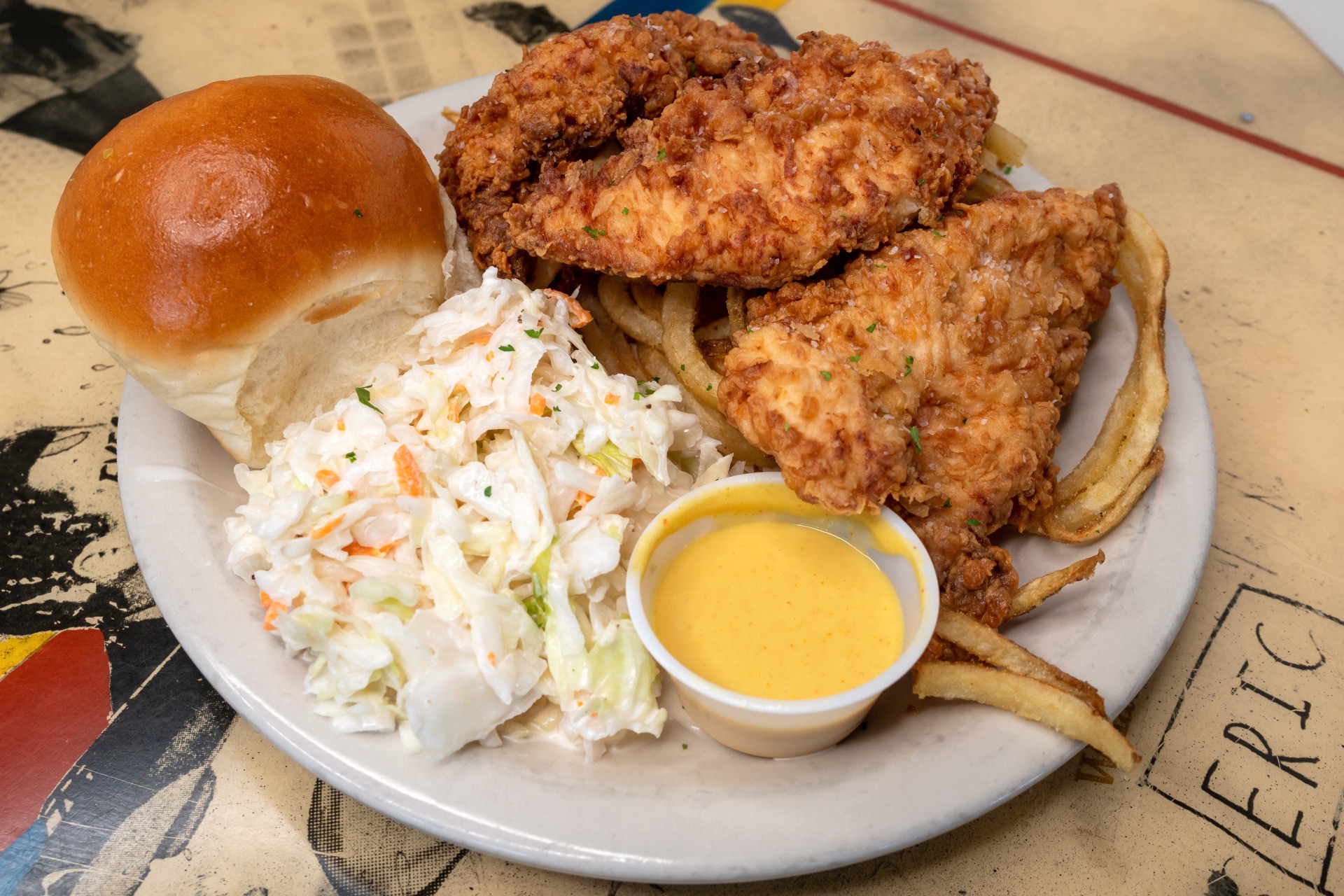 A plate lunch with chicken tenders, coleslaw and a roll